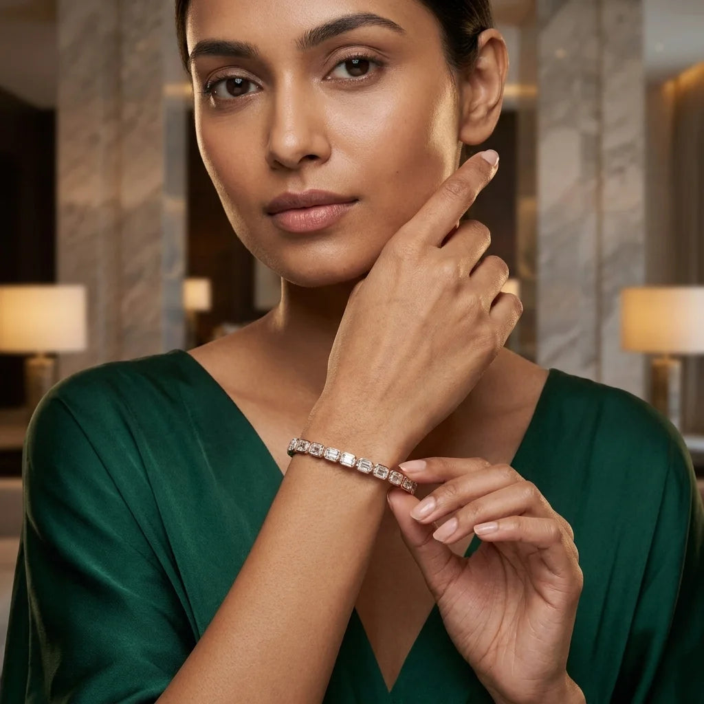 A woman in a dark green satin dress wears a delicate gold bracelet with clear diamonds , posing in a softly lit, elegant indoor setting.