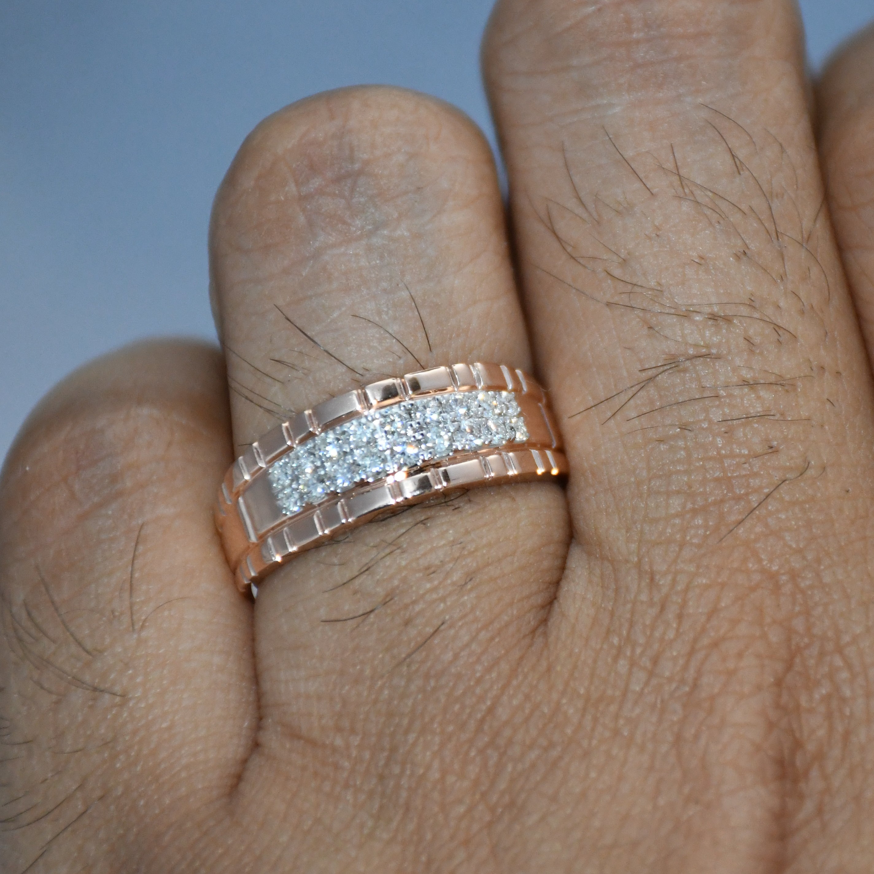 Hand wearing a rose gold ring with diamonds on a neutral background