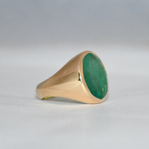 Gold ring with a green stone on a gray background