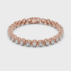 A rose gold tennis bracelet featuring oval brilliant-cut diamonds set in a continuous link design, shown against a plain white surface, is rotating parallel to the surface to show its all sides view.