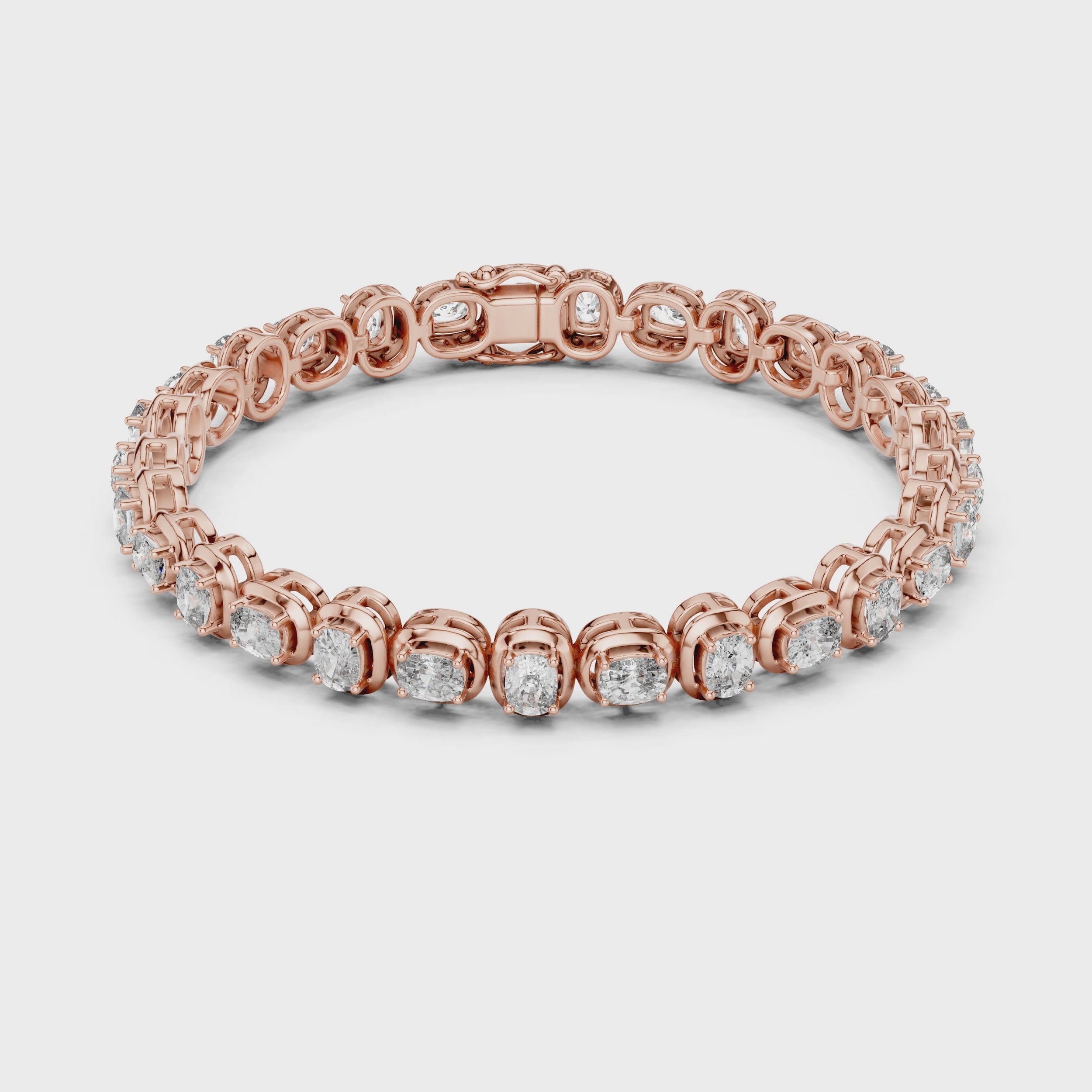 A rose gold tennis bracelet featuring oval brilliant-cut diamonds set in a continuous link design, shown against a plain white surface, is rotating parallel to the surface to show its all sides view.