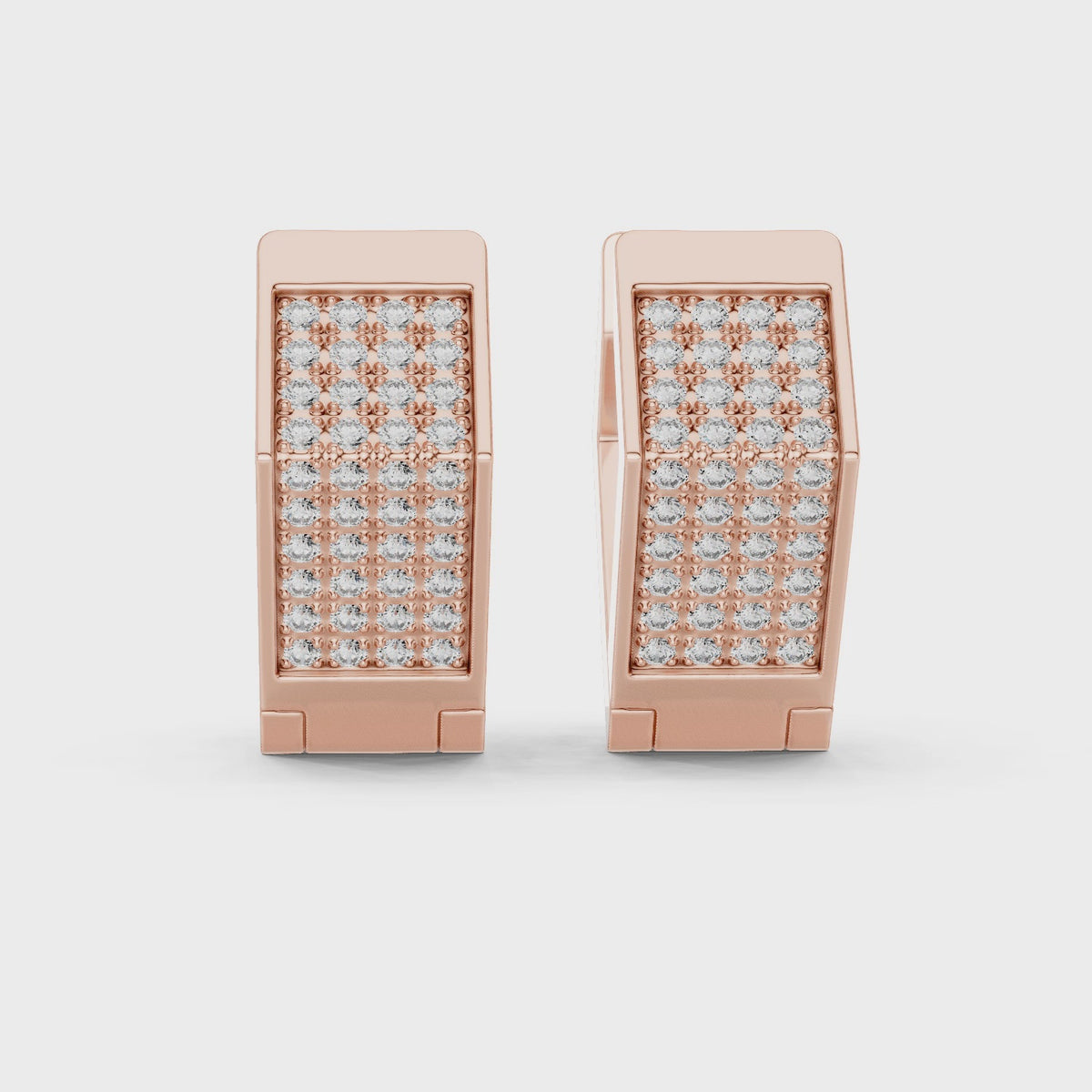 Rose gold earrings with diamond accents, is rotating parallel to the white surface.