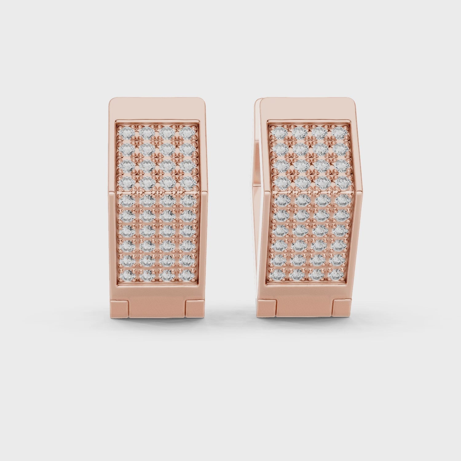 Rose gold earrings with diamond accents, is rotating parallel to the white surface.