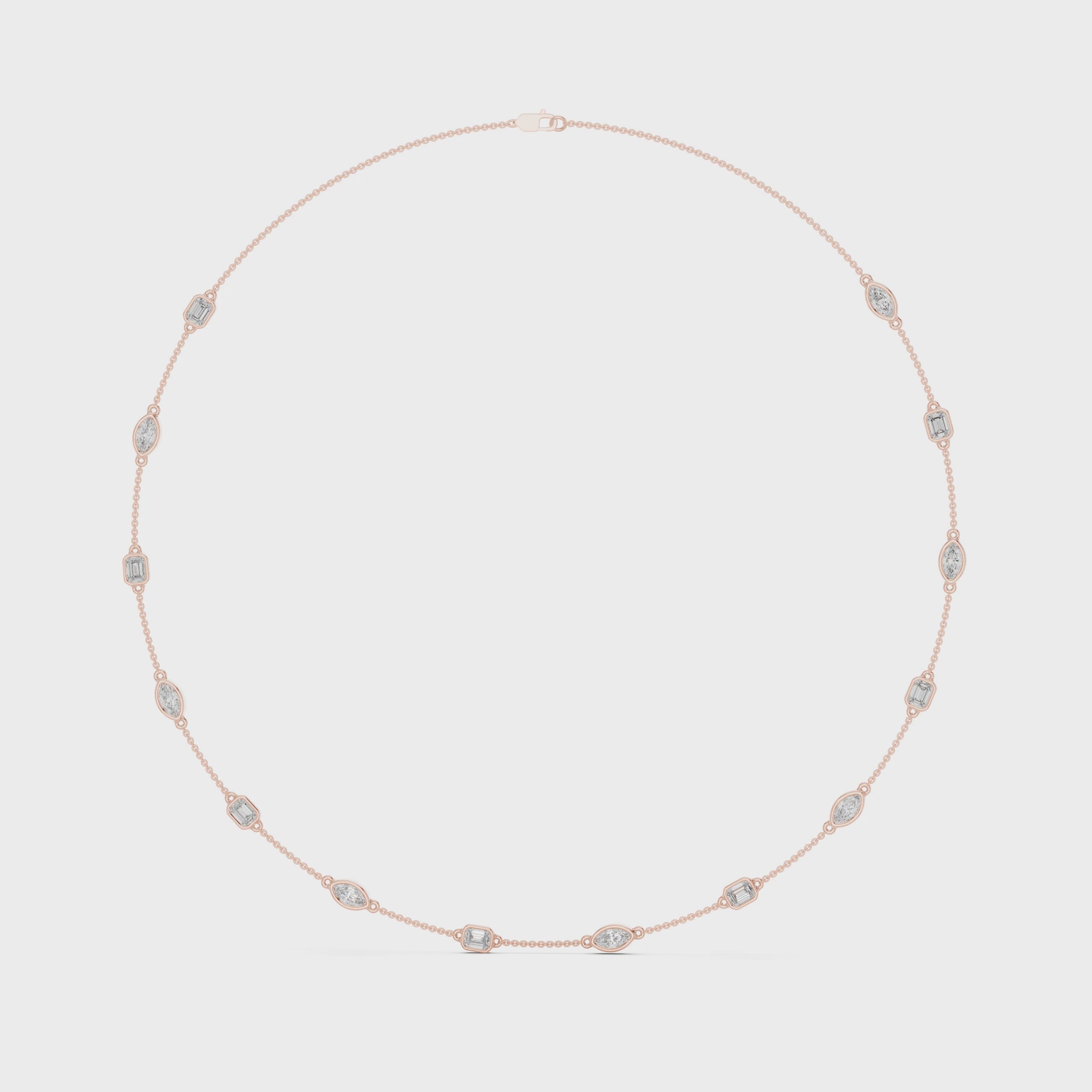 Rose gold necklace with emerald and marquise shape diamonds is rotating horizontally against a white surface.