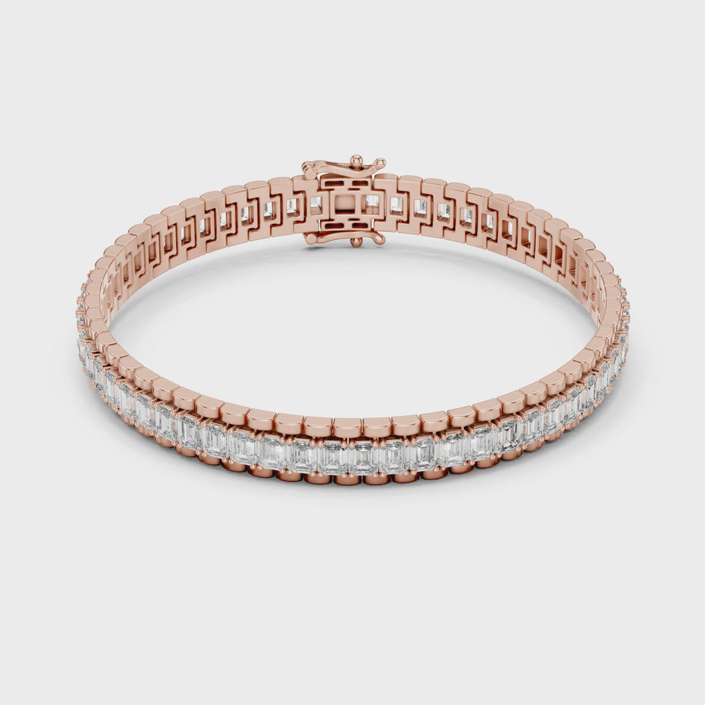 Rose gold bracelet with emerald diamond accents on a white surface is rotating parallel to the surface.