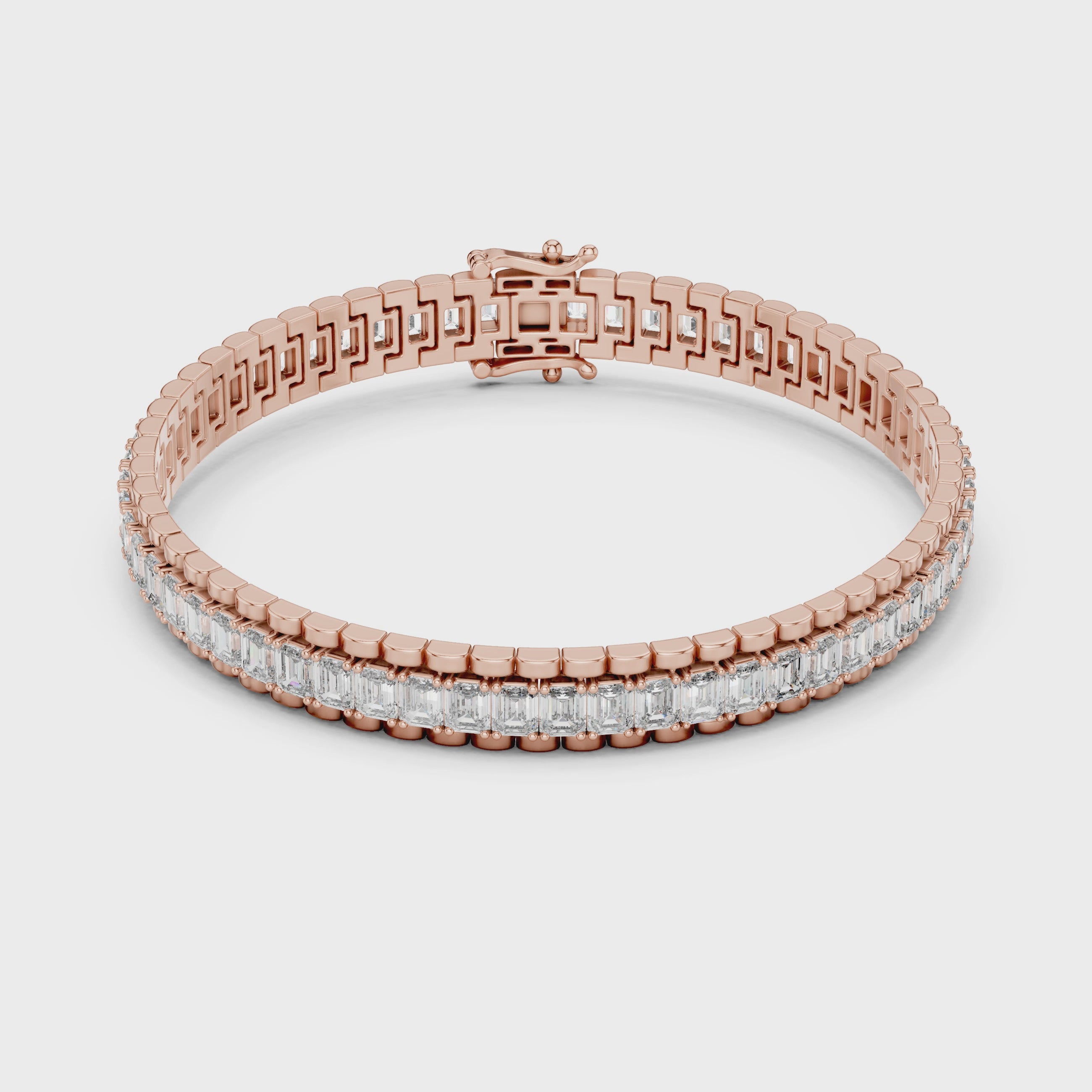 Rose gold bracelet with emerald diamond accents on a white surface is rotating parallel to the surface.