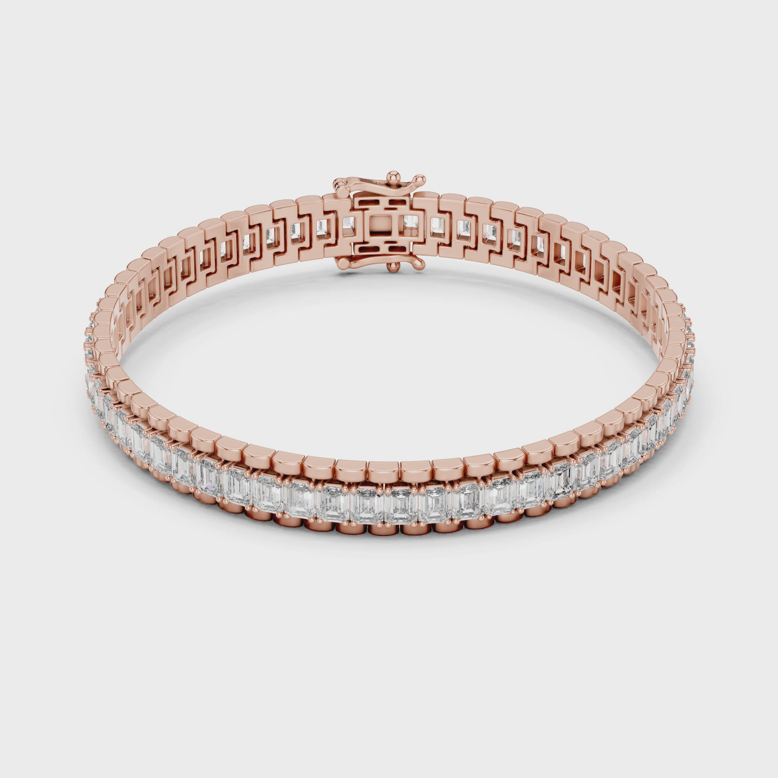 Rose gold bracelet with emerald diamond accents on a white surface is rotating parallel to the surface.