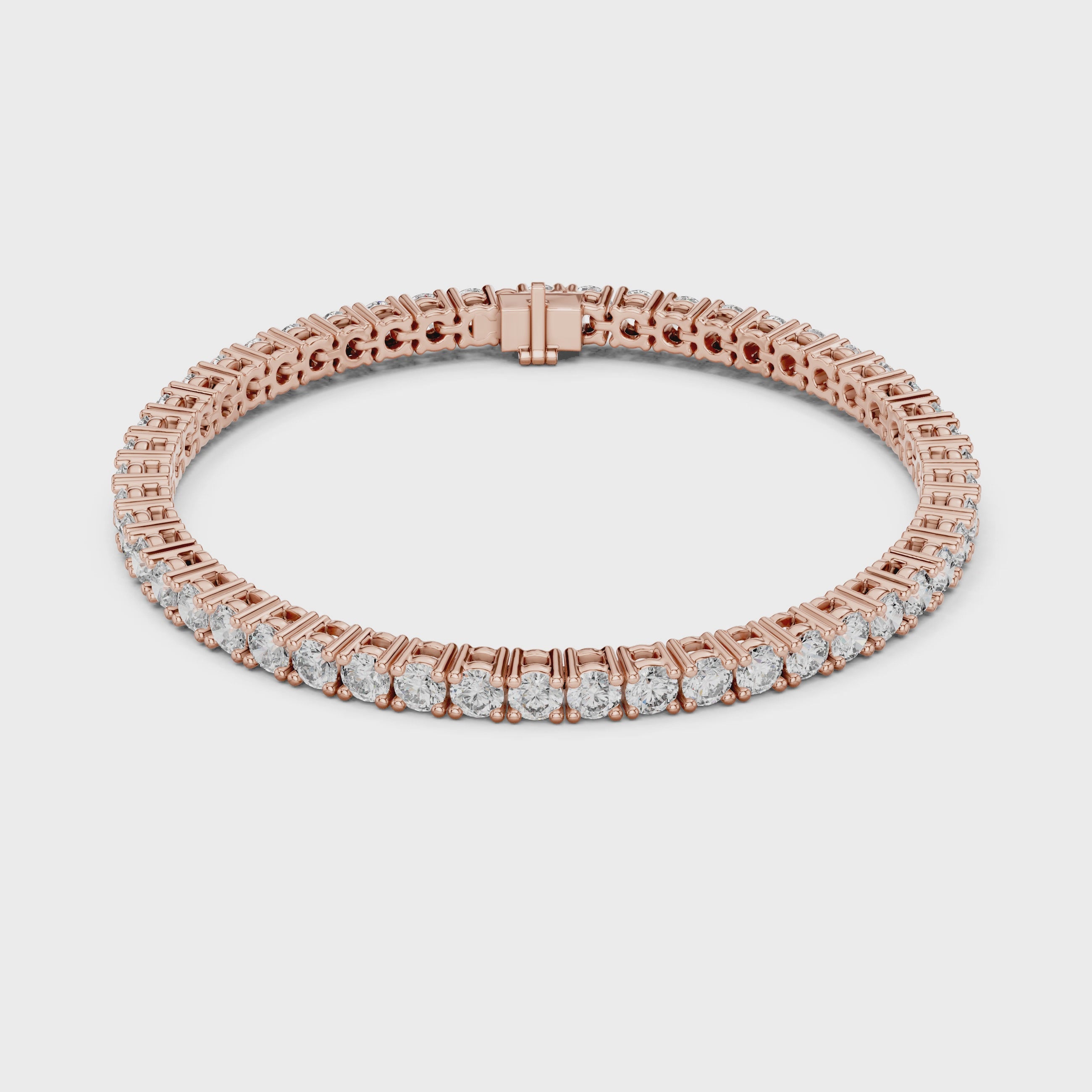 A rose gold tennis bracelet with a continuous row of round-cut clear diamonds, displayed on a clean white surface and rotating parallel to the surface.