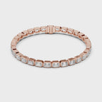 A rose gold tennis bracelet featuring rectangular emerald-shape clear diamonds in a continuous link design, shown on a plain white background and rotating parallel to the surface to show its view from every side.