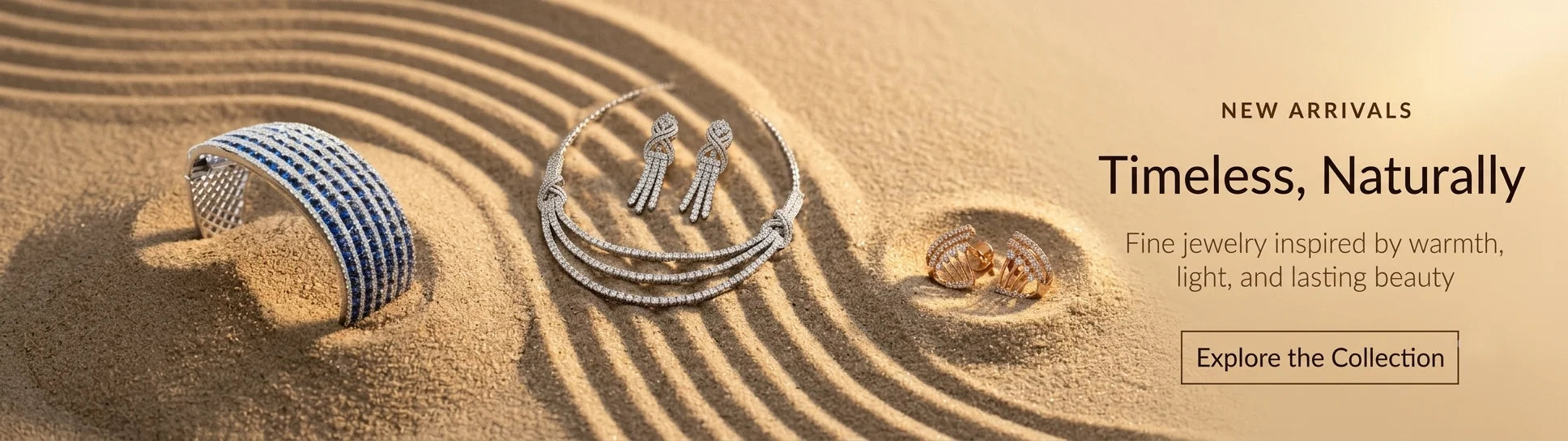 A promotional banner for jewelry featuring a silver-toned ring with a blue-and-white striped band, a white gold-toned hoop with matching necklace, and a small gold-toned piece, arranged on sand with ripples. Text on the right reads 'NEW ARRIVALS Timeless, Naturally Fine jewelry inspired by warmth, light, and lasting beauty.