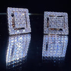 Pair of diamond earrings on a reflective black surface