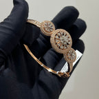 Gold and diamond bracelet held by a gloved hand on a neutral background