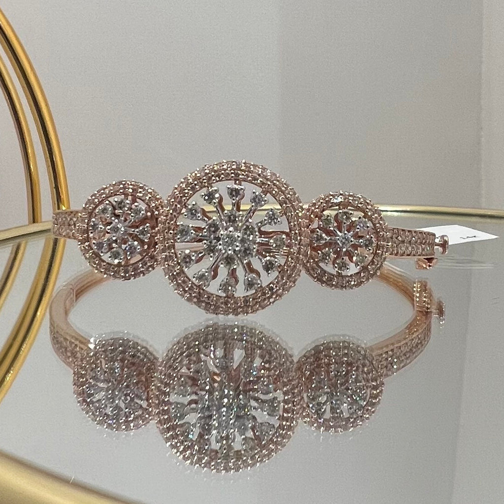 Rose gold bracelet with diamond accents on a reflective surface