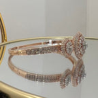 Rose gold bracelet with diamond accents on a reflective surface