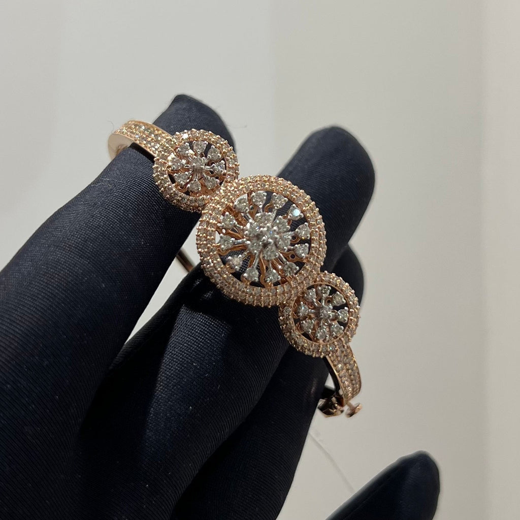 Rose gold bracelet with diamond accents on a black glove against a neutral background