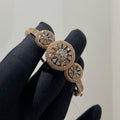 Rose gold bracelet with diamond accents on a black glove against a neutral background