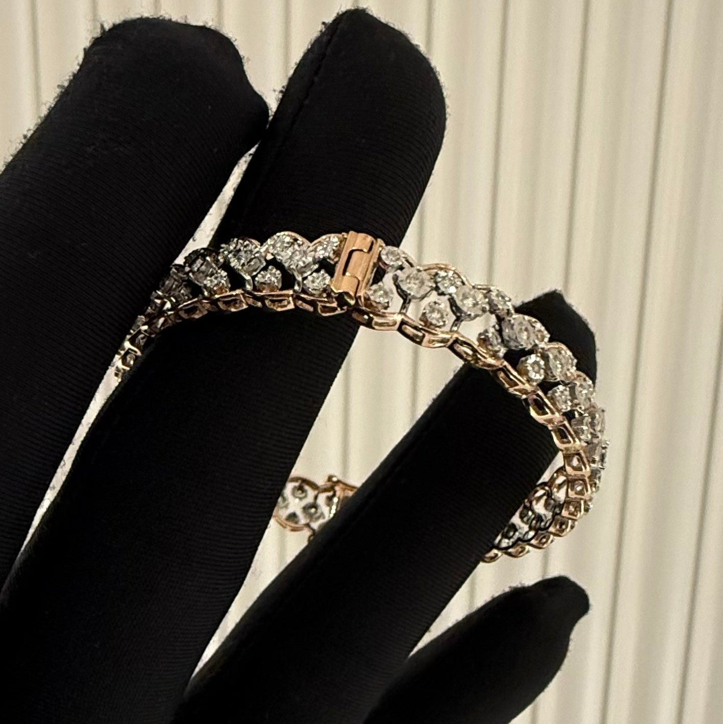 Gold bracelet with diamonds on a black-handled glove against a white background