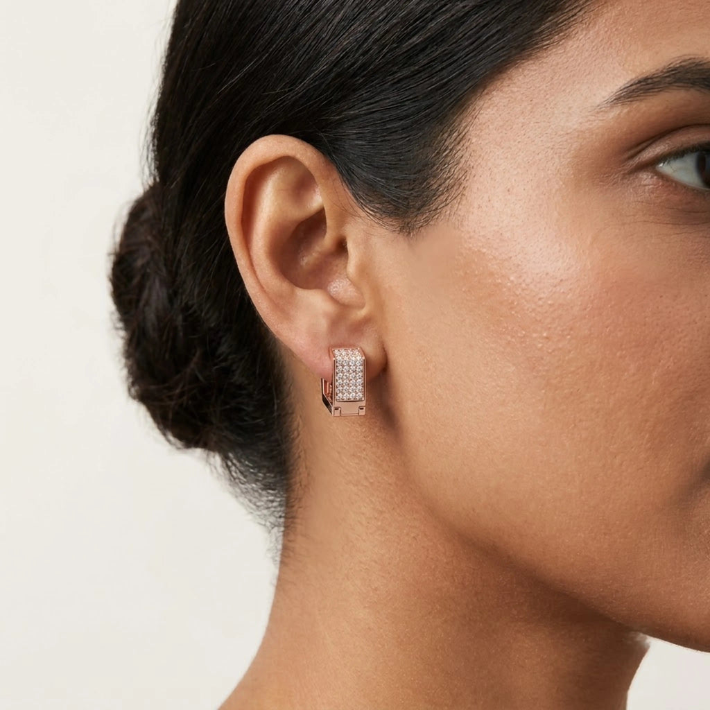 Rose gold earrings with diamond accents is worn by a woman against a white background.