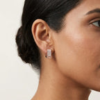 Rose gold earrings with diamond accents is worn by a woman against a white background.