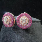 Pair of round diamond earrings with pink gemstones on a dark background