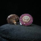 Pair of round diamond earrings with pink gemstones on a dark background