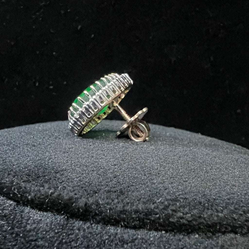 gold ring with green gemstones and diamonds on a black background
