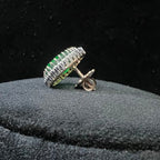 gold ring with green gemstones and diamonds on a black background