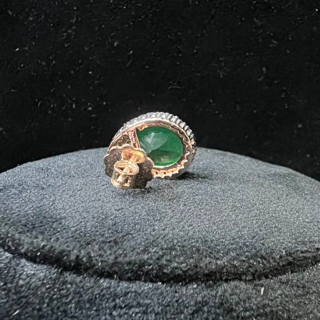 Gold earring with a green gemstone and diamonds on a black background