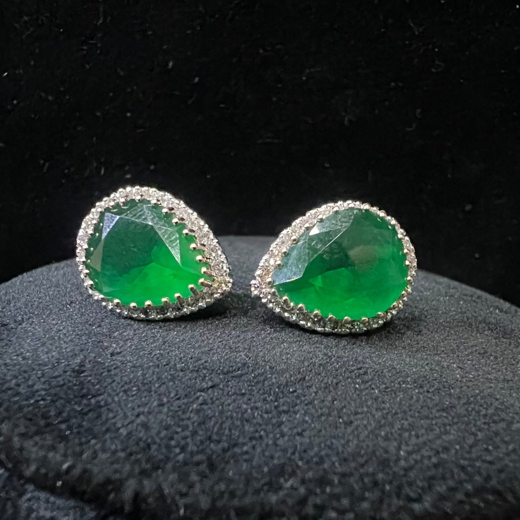 Pair of green gemstone and diamonds earrings on a black background