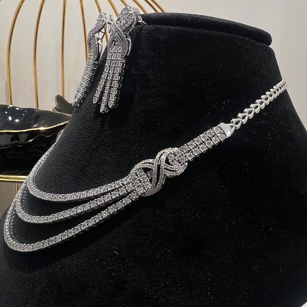 White gold necklace and earrings on a black velvet stand with a blurred background