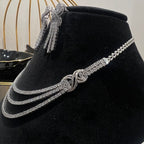 White gold necklace and earrings on a black velvet stand with a blurred background