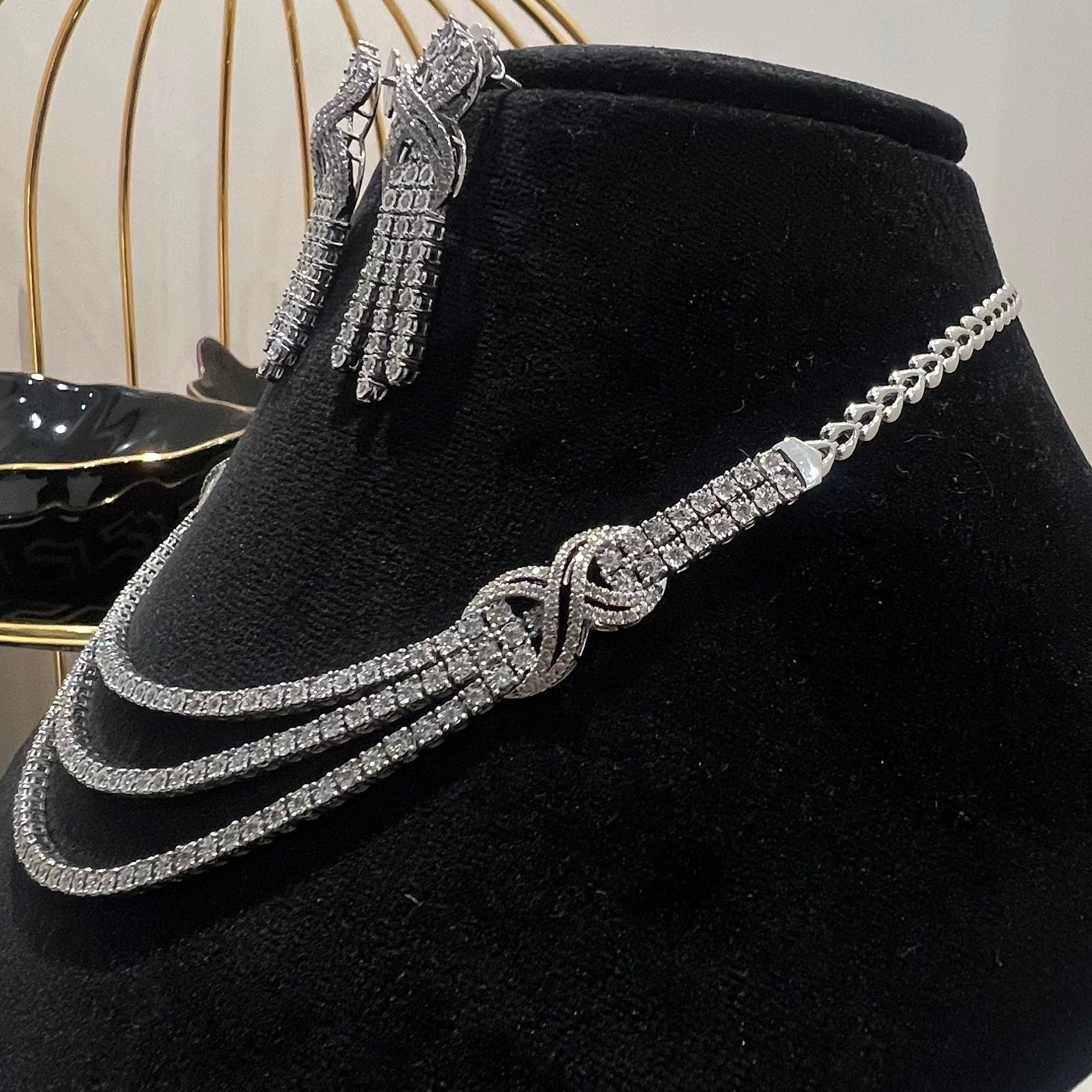 White gold necklace and earrings on a black velvet stand with a blurred background