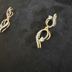 Gold earrings with diamond accents on a black background