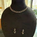 Gold necklace and earrings on a black mannequin bust.