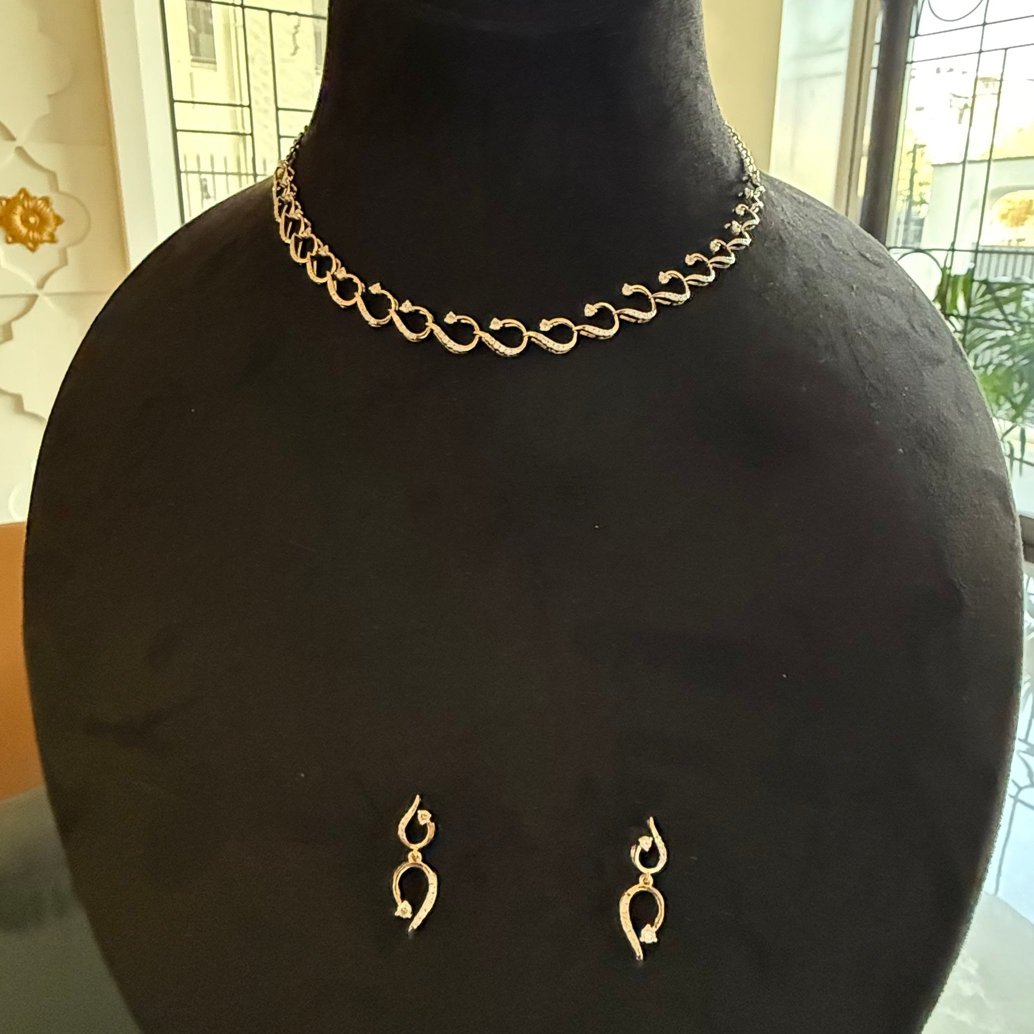 Gold necklace and earrings on a black mannequin bust.