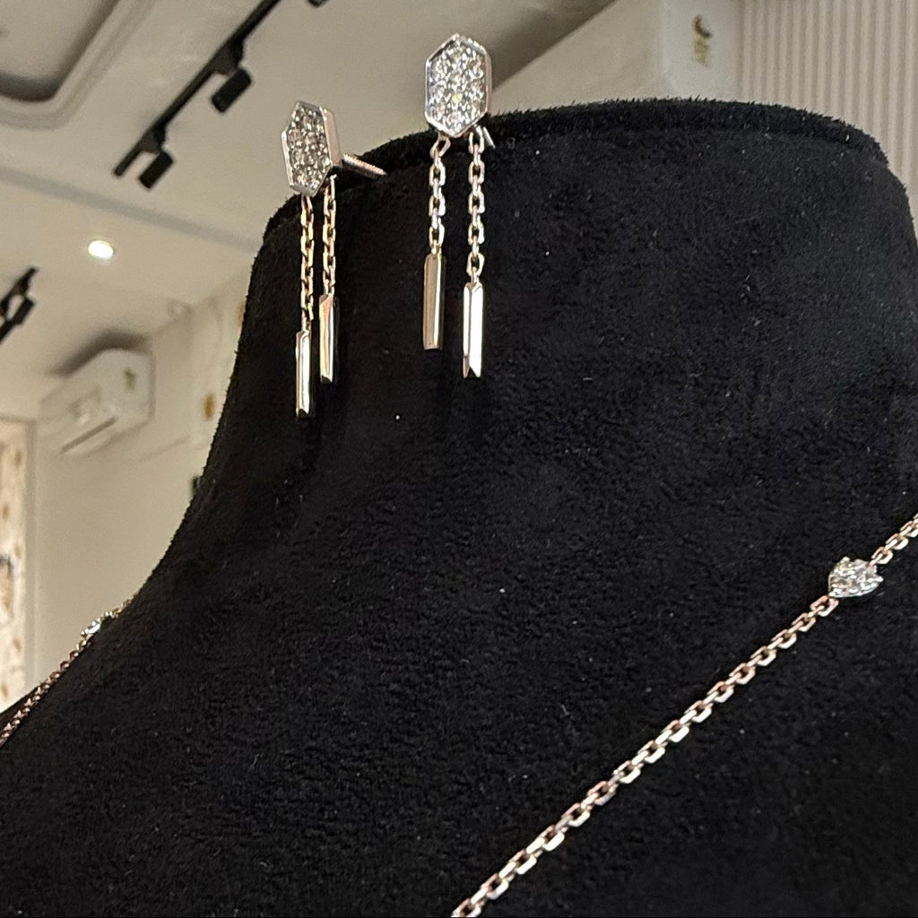 diamond chain earrings on a black mannequin bust.