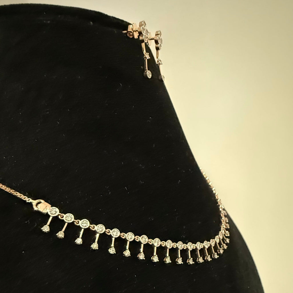 Gold diamond necklace and earrings with fringe design on a black stand against a beige background