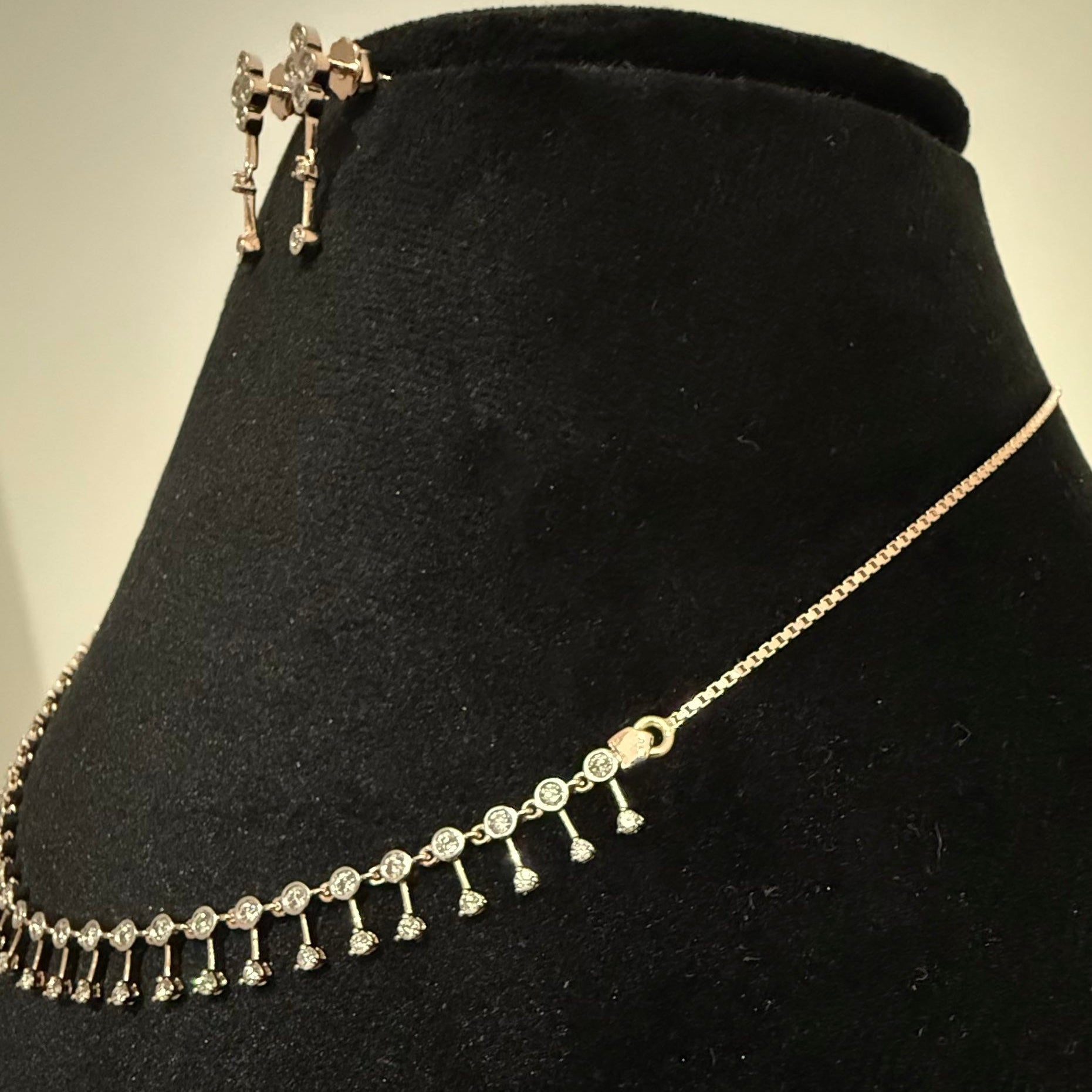 Gold necklace and earrings with diamonds on a black velvet stand