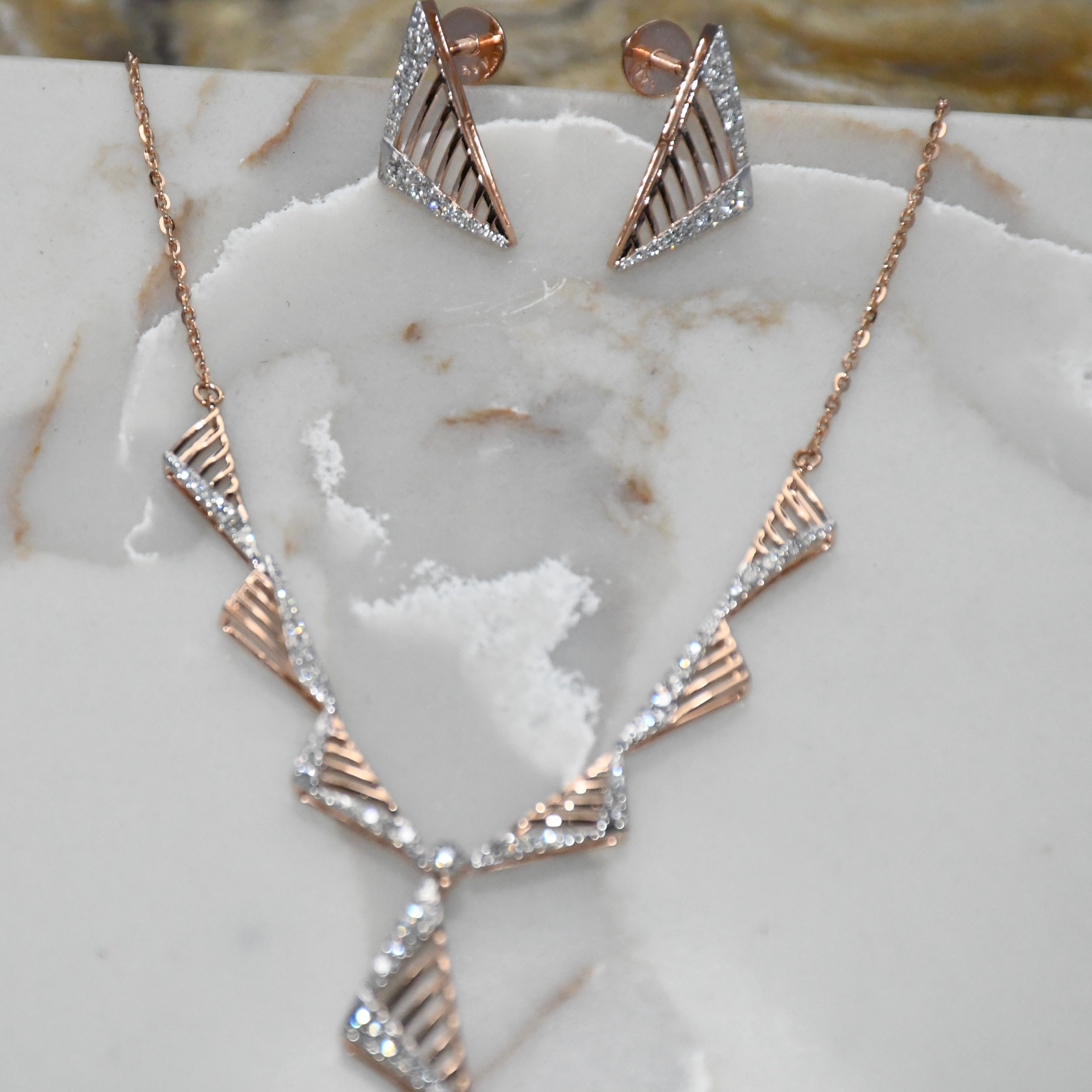 Rose gold necklace and earrings on a marble surface