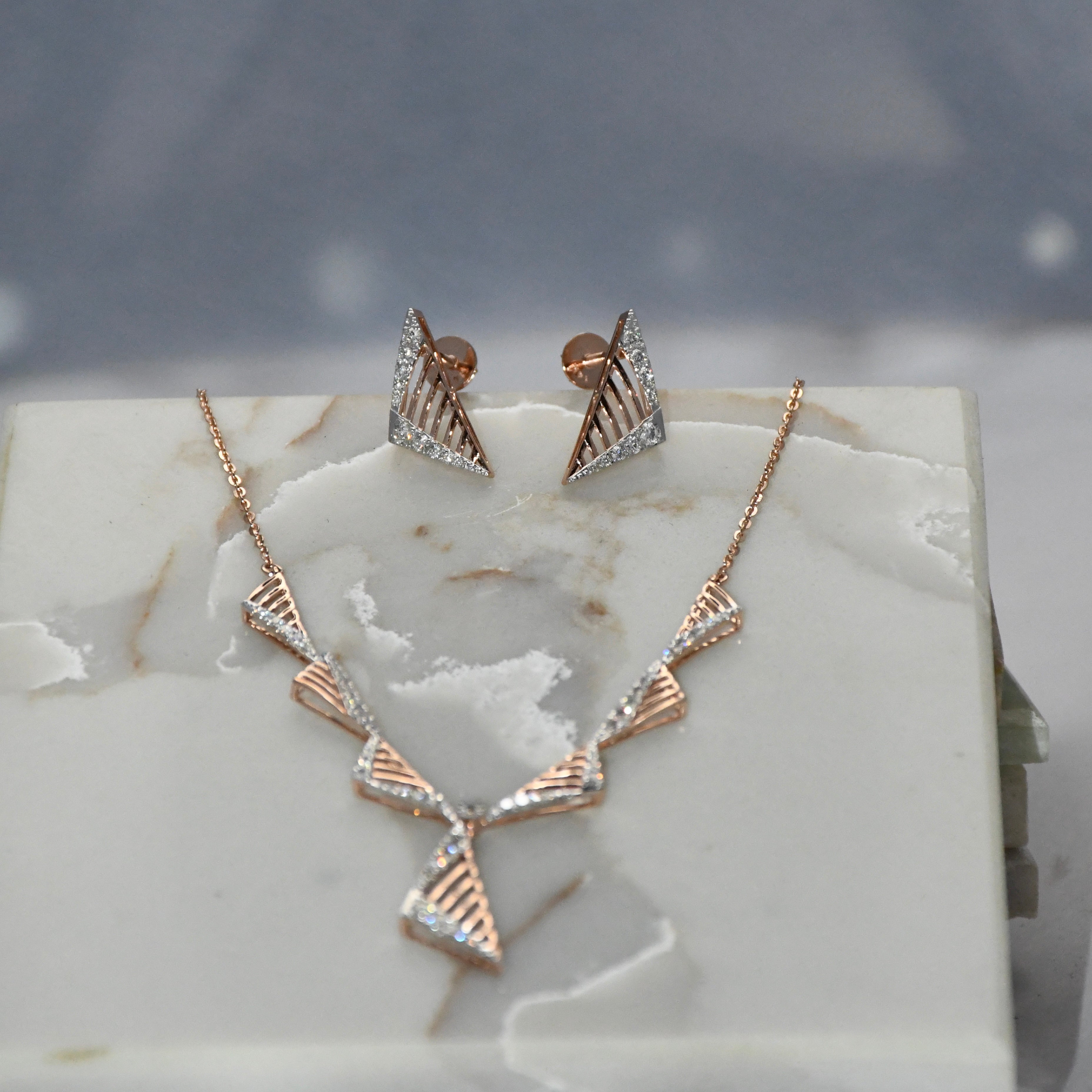 Rose gold necklace and earrings on a marble surface