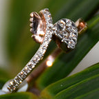 Close-up of a pave set diamonds gold ring with leaves on a green leafy background