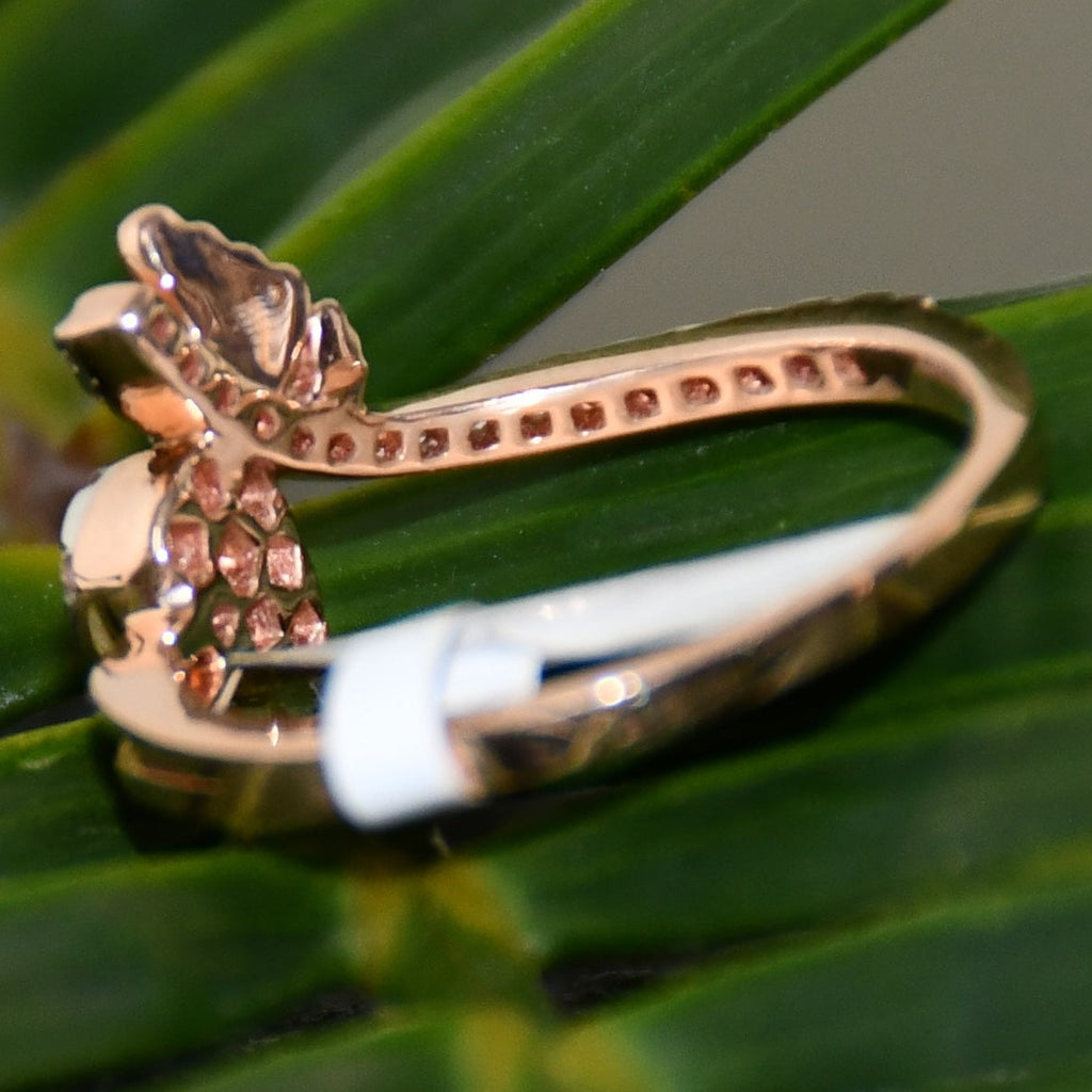 Rose gold ring with diamonds on a green leaf