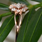 Rose gold ring with diamond accents on a green leaf background