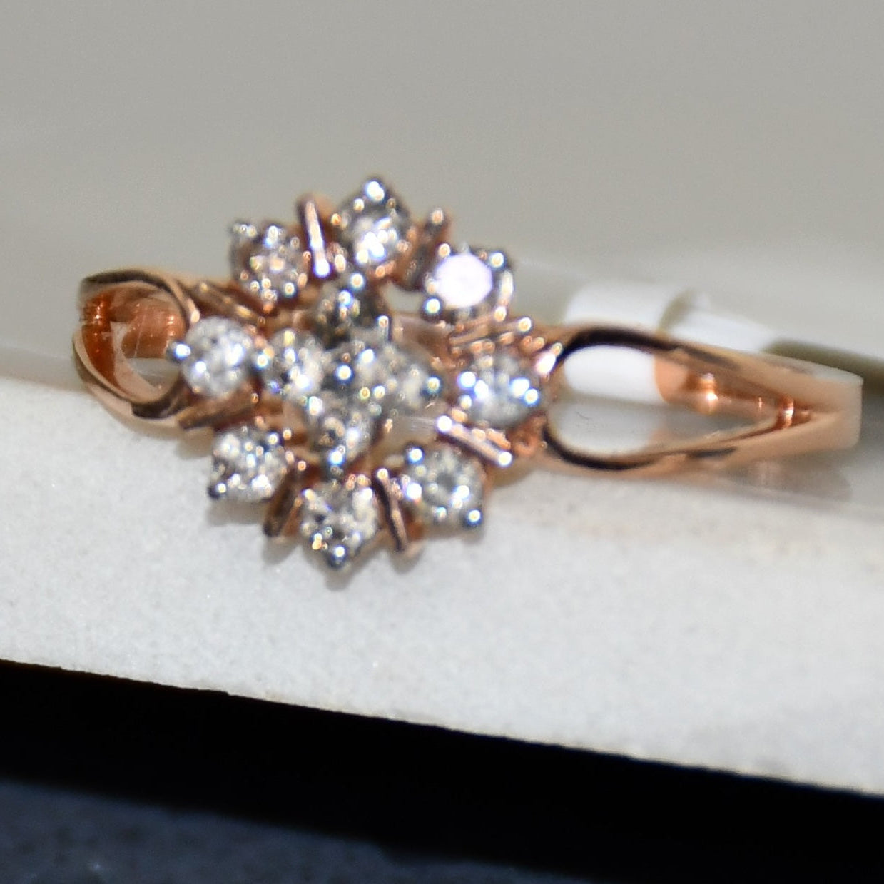Rose gold ring with diamond accents on a white stone surface