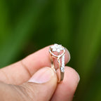 Rose gold ring with diamonds held between fingers against a blurred green background