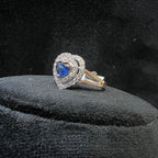 Heart-shaped diamond ring with a blue gemstone on a black cushion