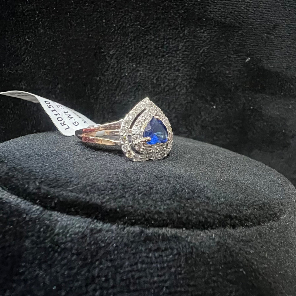 Gold diamond ring with a blue gemstone on a black velvet cushion
