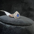Gold diamond ring with a blue gemstone on a black velvet cushion