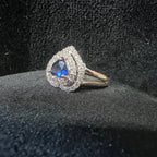 Ring with blue gemstone and diamond accents on a black textured surface