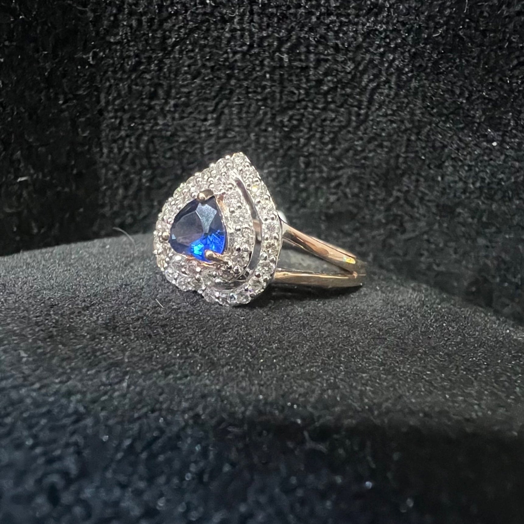 Ring with blue gemstone and diamond accents on a black textured surface